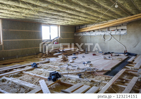 Big spacious light empty attic room under construction and renovation. Mansard floor and ceiling insulation with rock wool. Fiberglass insulation staff in wooden frame for cold barrier. Big spacious light empty attic room under construction and renovation. Mansard floor and ceiling insulation with rock wool. Fiberglass insulation staff in wooden frame for cold barrier. 123214151