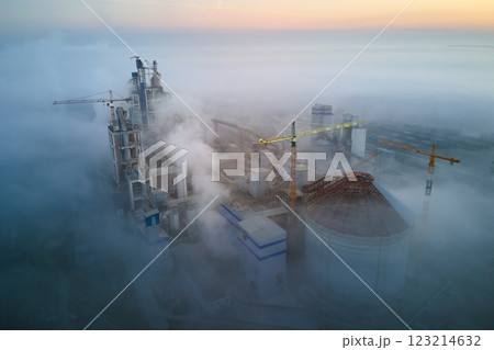 Aerial view of cement factory with high concrete plant structure and tower crane at industrial production site on foggy morning. Manufacture and global industry concept. Aerial view of cement factory with high concrete plant structure and tower crane at industrial production site on foggy morning. Manufacture and global industry concept. 123214632