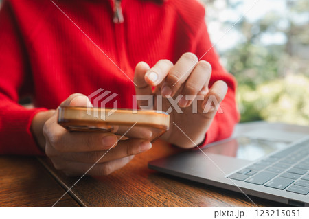Hands interacting with smartphone and laptop, capturing a moment of digital connectivity in a relaxed cafe environment. Hands interacting with smartphone and laptop, capturing a moment of digital connectivity in a relaxed cafe environment. 123215051