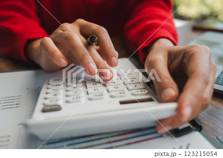 Hands using a calculator on financial documents, ideal for themes of budgeting, finance, and analysis. Hands using a calculator on financial documents, ideal for themes of budgeting, finance, and analysis. 123215054