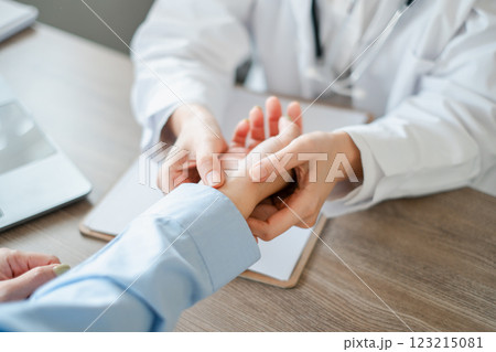 Close-up of a healthcare professional checking a patient's wrist, focusing on medical examination and patient care. 123215081