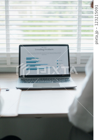Business professionals reviewing data on a laptop displaying graphs and charts in a bright office environment. 123215091