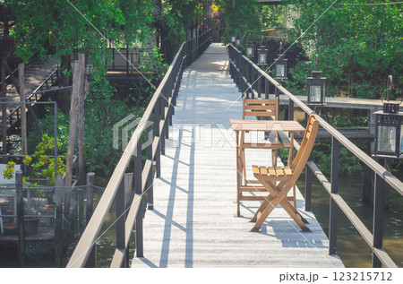 Serene walkway with wooden chair by water Serene walkway with wooden chair by water 123215712