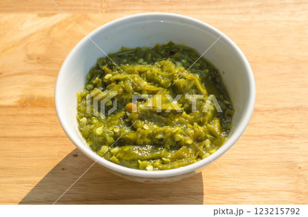 Green chutney in a white bowl on wooden surface Green chutney in a white bowl on wooden surface 123215792
