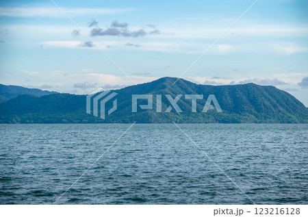 Scenic view of mountains over a calm sea. Scenic view of mountains over a calm sea. 123216128
