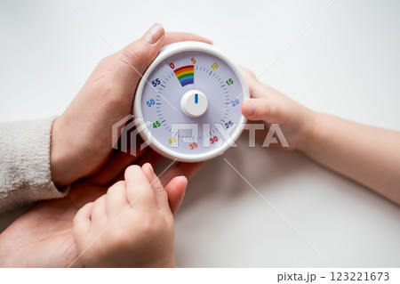Adult and child hands holding colorful timer on white background 123221673