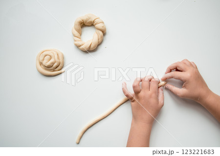 Child forming dough into shapes on white surface Child forming dough into shapes on white surface 123221683