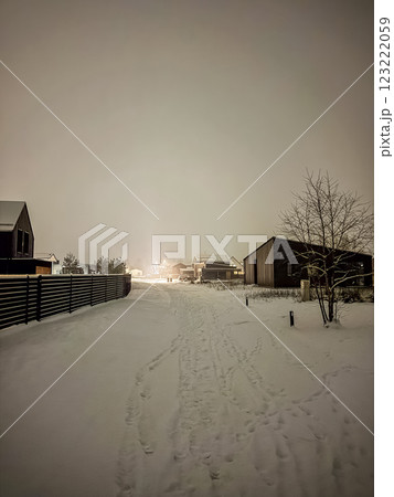 Snow-covered village street glowing under warm night lights in winter. High quality photo 123222059