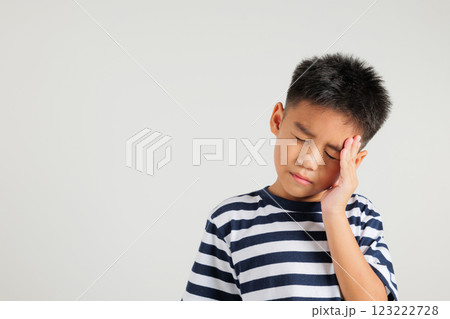 Portrait of Asian young kid boy sad tired strain face holding hold head by hands, stress primary child person unhappy closed eyes problem headache, studio shot isolated on white background Portrait of Asian young kid boy sad tired strain face holding hold head by hands, stress primary child person unhappy closed eyes problem headache, studio shot isolated on white background 123222728