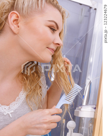 Woman combing her long hair in bathroom 123224679
