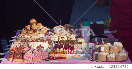 Assorted Colorful Pastries and Cakes Displayed on a Table at an Outdoor Market Assorted Colorful Pastries and Cakes Displayed on a Table at an Outdoor Market 123224725