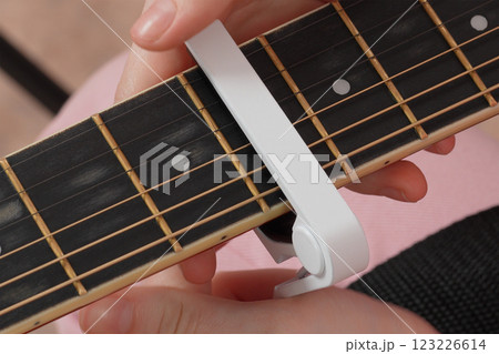 Female fingers applying capodastro to six string acoustic classical guitar 123226614