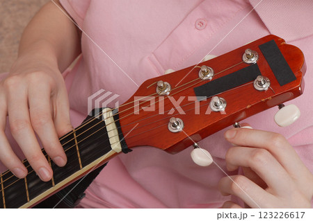 Extreme close-up woman's fingers tuning acoustic guitar. Daily routine process Extreme close-up woman's fingers tuning acoustic guitar. Daily routine process 123226617