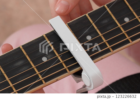 Female fingers applying capodastro to six string acoustic classical guitar 123226632