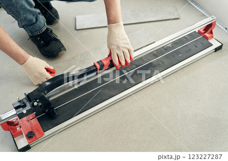 An unrecognizable worker prepares a machine for working with floor tiles. With space to copy. High quality photo 123227287