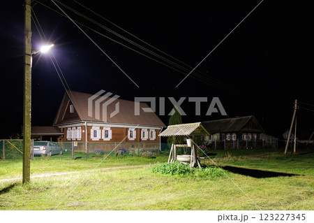 Nighttime Village Scene with Old Well and Wooden Houses Nighttime Village Scene with Old Well and Wooden Houses 123227345