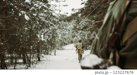 Usa Army Soldiers Of World War Ii. Heroes Of War. Re-enactors Dressed As American Infantry Soldier Marching Through Forest Road In Cold Winter Day. Group Of Usa Soldiers Marching Country Road 123227676