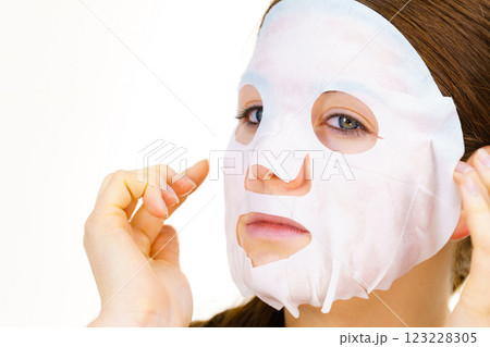 Woman applying sheet mask on face 123228305