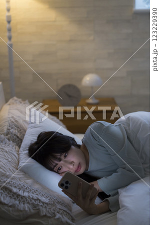 ベッドでスマホを見る女性 123229390