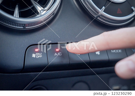 Car Interior Climate Control System Featuring Air Conditioning Control Buttons for Comfort. A closeup view of a finger operating the controls for the cars air conditioning system and air vents 123230290