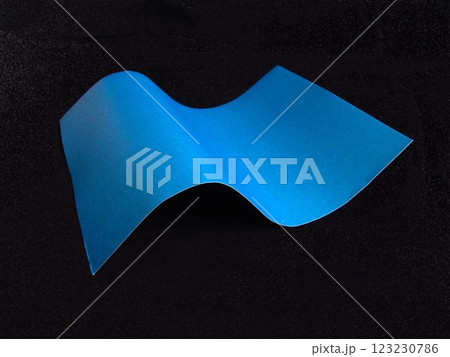 Wavy paper sheet over black background 123230786
