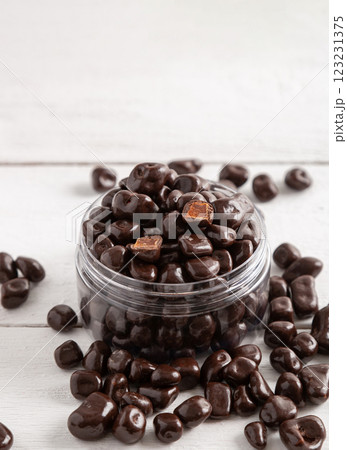 Dried fruits and berries in brown chocolate glaze. Candies on a white wooden background. 123231375