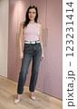 Pretty brunette 51 years old in pink high-heeled shoes in a pink fashionable T-shirt and grey jeans posing near a pink wardrobe 123231414