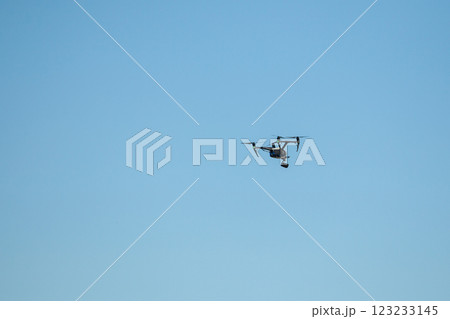 Drone flying with a camera against blue sky Drone flying with a camera against blue sky 123233145