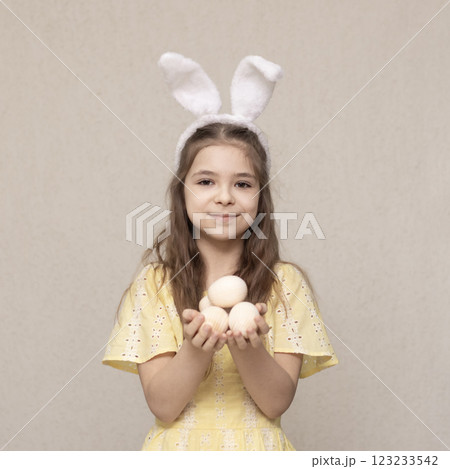 Young girl holding decorative eggs wearing bunny ears for Easter celebration 123233542