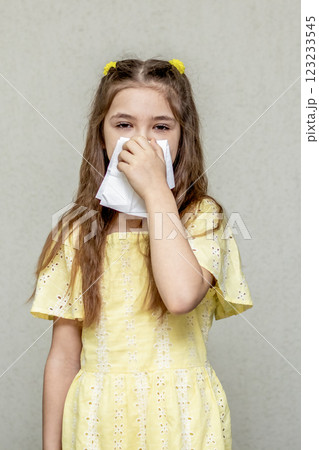 Young girl holding tissue reflecting possible allergies or seasonal discomfort 123233545