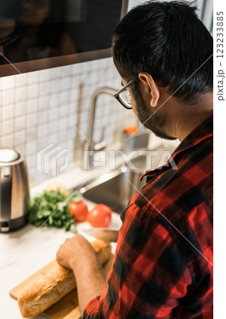 Close-up Indian or latino man cooking breakfast while standing at the kitchen at home, rear view 123233885