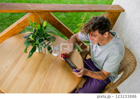 Young man playing video game drinking water at terrace in summer day. Technology and game addiction concept 123233886