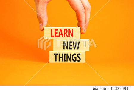 Learn new things symbol. Concept words Learn new things on beautiful wooden blocks. Beautiful orange background. Businessman hand. Business motivational learn new things concept. Copy space. 123233939