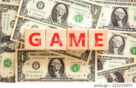 Game symbol. Concept word Game on beautiful wooden blocks. Dollar bills. Beautiful background from dollar bills. Business, lifestyle and game concept. Copy space. Game symbol. Concept word Game on beautiful wooden blocks. Dollar bills. Beautiful background from dollar bills. Business, lifestyle and game concept. Copy space. 123233955