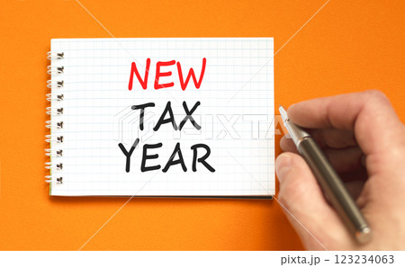 New tax year symbol. Concept words New tax year on beautiful white note. Beautiful orange background. Black pen. Businessman hand. Business new tax year concept. Copy space. 123234063