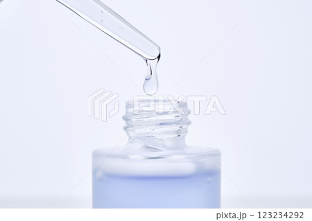 The blue serum drips from the dropper into the bottle. 123234292