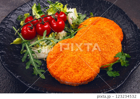 crispy fried fish cutlets, fish burgers, on a black plate, with fresh lettuce leaves, arugula and cherry tomatoes, homemade, no people, 123234532