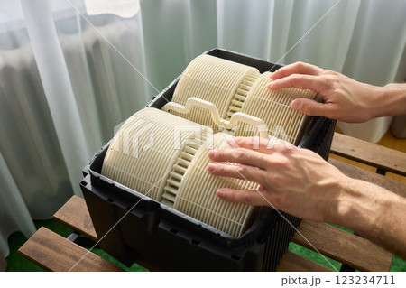 Hands are carefully handling industrial filters while inside a well-organized storage box 123234711