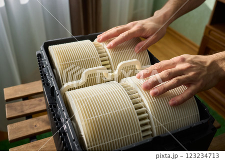 Hands are carefully handling industrial filters while inside a well-organized storage box 123234713