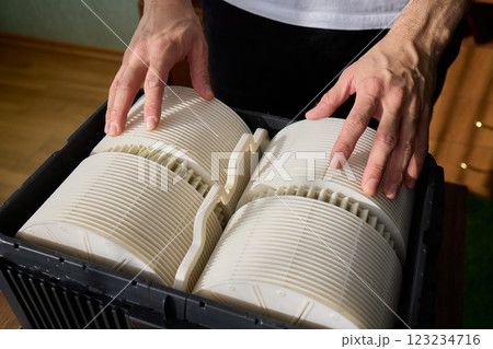 Hands are carefully handling industrial filters while inside a well-organized storage box 123234716