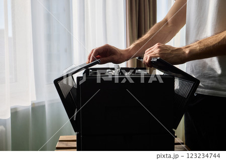 A person diligently assembling a contemporary black cooling device with precision and focus A person diligently assembling a contemporary black cooling device with precision and focus 123234744
