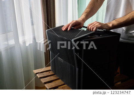 A person diligently assembling a contemporary black cooling device with precision and focus A person diligently assembling a contemporary black cooling device with precision and focus 123234747