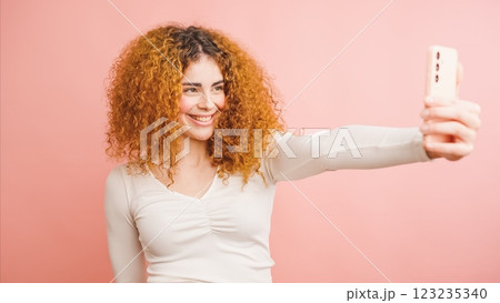 Young woman taking a selfie with smartphone on pink background Young woman taking a selfie with smartphone on pink background 123235340