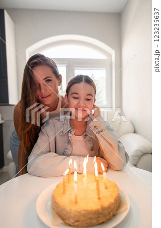 Birthday Cake Sisters Home Celebration: Two sisters celebrate a birthday with a lit cake indoors, capturing a joyful family moment. Birthday Cake Sisters Home Celebration: Two sisters celebrate a birthday with a lit cake indoors, capturing a joyful family moment. 123235637