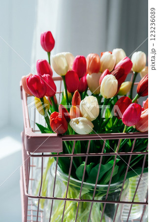 tulips in a pink supermarket trolley on a light background. bouquet of tulip buds in an iron basket 123236089
