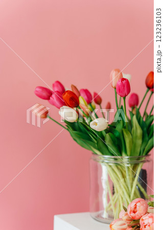 colored tulips on a pink background. bouquet of tulip buds in a glass vase on a colored background 123236103