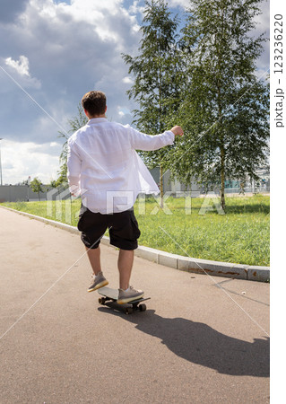 Young man in white shirt skateboarding in park. Vertical photo. High quality photo 123236220