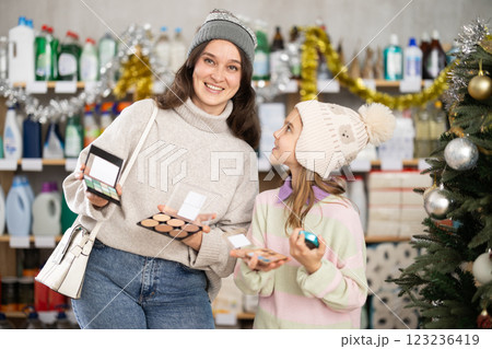 Woman with child family selects and studies label makeup cosmetic agent on New Year Eve Woman with child family selects and studies label makeup cosmetic agent on New Year Eve 123236419