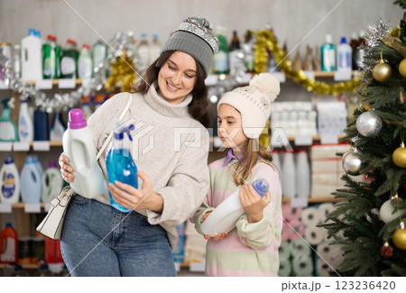 Woman with daughter choosing detergent and spray in decorated store 123236420