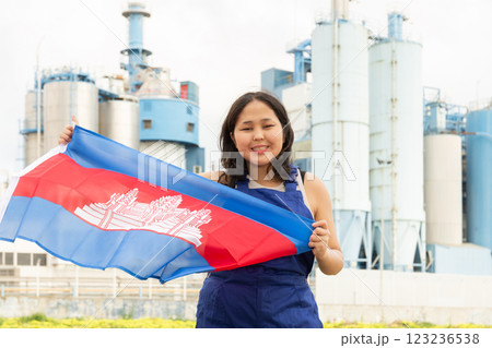 Happy young woman with flag of Cambodia against background of factory Happy young woman with flag of Cambodia against background of factory 123236538